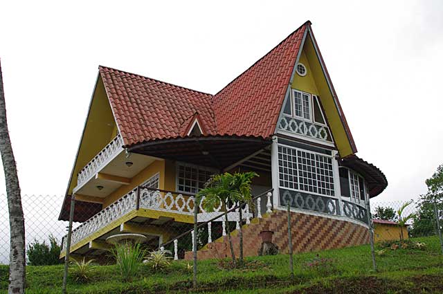 Photo of a 2 story country house painted in yellow and white with high roofs