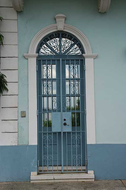 Photo Example of a traditional old door in light blue color with glass panels and additional decorative metal security door, this image was taken in the old colonial part of Panama City.