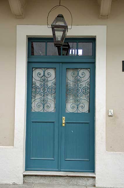 Photo Example of a traditional old door in light blue with glass panels and a decorative metal security cover.