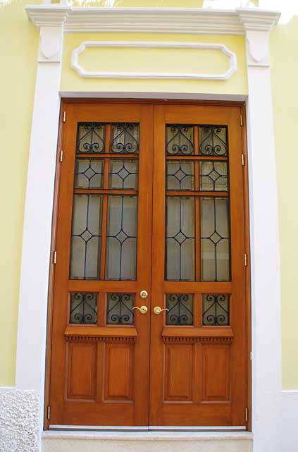 Photo Example of an beautifully renovated two wing old door in natural wood finish and glass panels with decorative metal protection