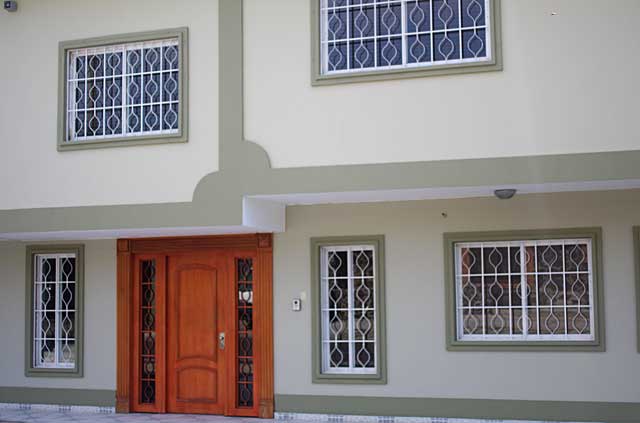 Photo Example of a big wooden door with glass side panels with decorative metal protection