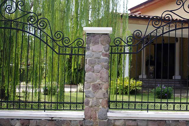 Photo Example of a decorative fence around a town house with natural stone pillars and black metal bars