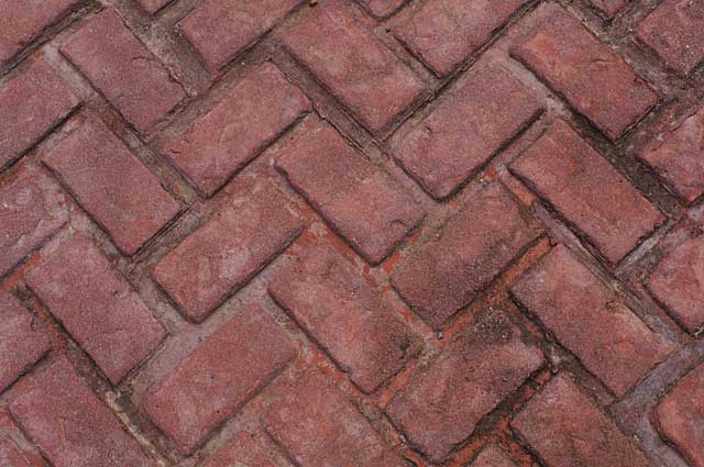 Example of a rustic stamped into the concrete floor that is imitating red bricks and is used on an exterior walkway