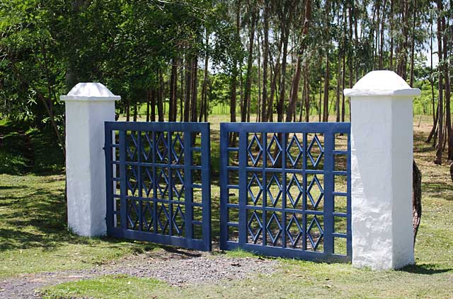 Photo of a simple gate made of white stone pillars and blue metal doors
