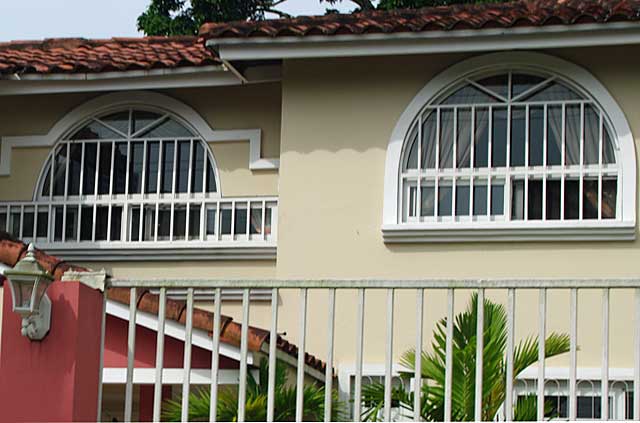 Photo of a house with a metal security fence and metal window frames adjusted to the window shapes.
