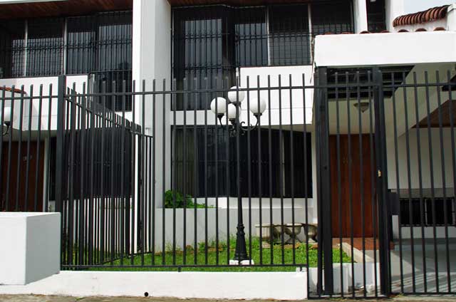 Modern house with a black metal security fence and black metal window security covers