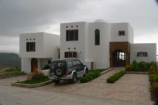 Photo example of a modern two story house painted in white in combination with natural stones, at a top location, overlooking the Pacific Ocean