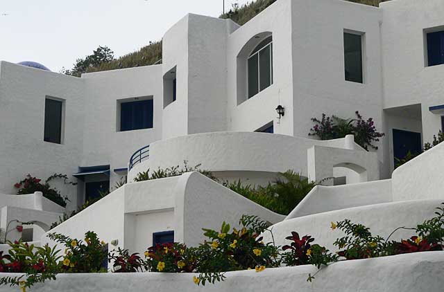 Photo example of a modern apartment complex painted in white in combination with deep blue, at a top location, overlooking the Pacific Ocean