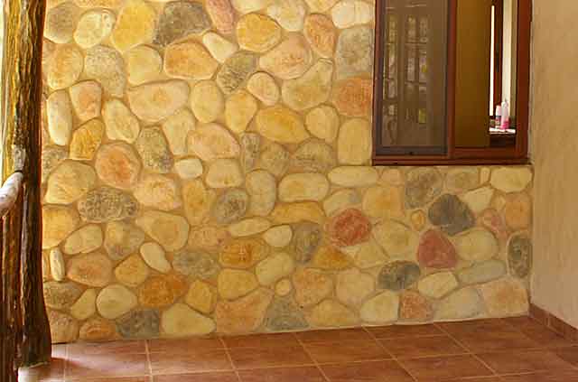Photo example of a wall on country house built with beige and redish river stones. Real or Fake?